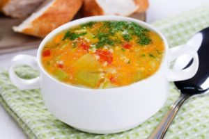 Ciorbă de dovlecel a la grec în bol alb, alături de pâine și verdeață
