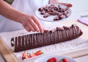 Ruladă cu căpșuni și ciocolată albă decorată cu ciocolată neagră