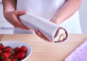 Ruladă cu căpșuni și ciocolată albă împachetată în hârtie de copt