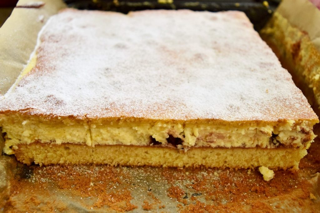 Prăjitura turnată cu brânză și stafide, pudrată cu zahăr