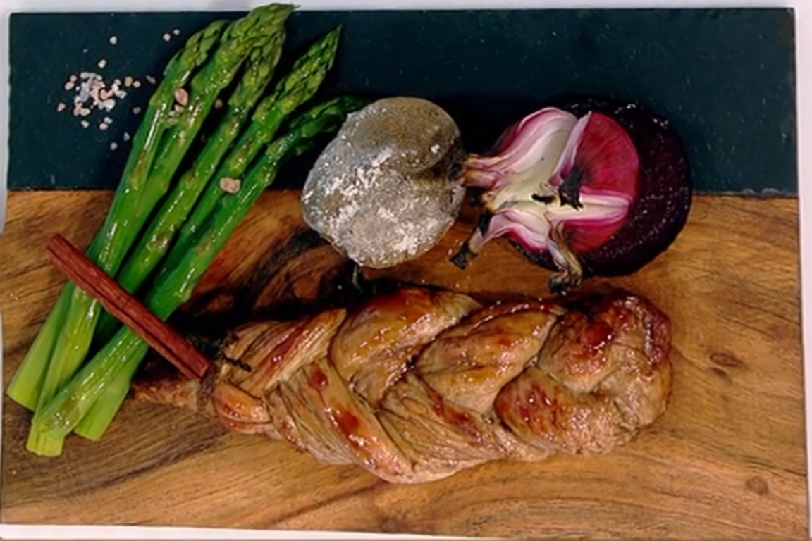 Friptură din mușchiuleț de porc împletit alături de sparanghel, cartofi și ceapă roșie