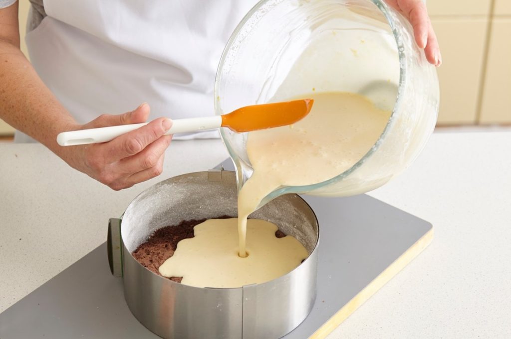 Pasul de adăugare a cremei de brânză cu portocale peste blatul de cheesecake