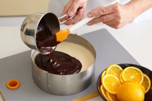 Pasul de adăugare glazură peste cheesecake cu portocale și ciocolată