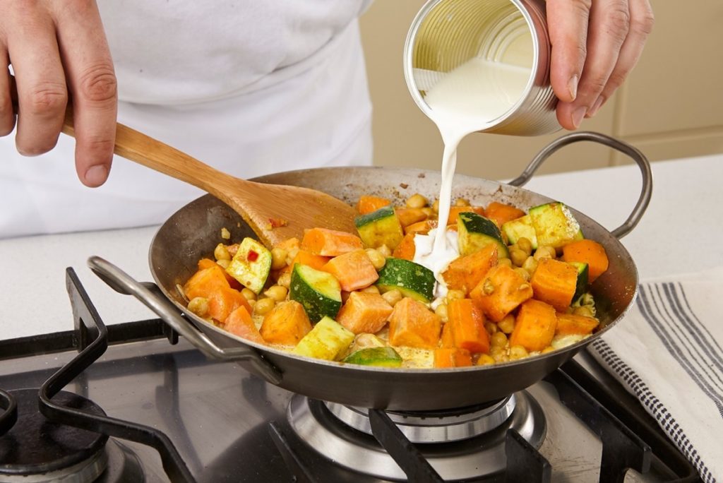 Adăugare smântână vegetală peste curry de năut cu legume