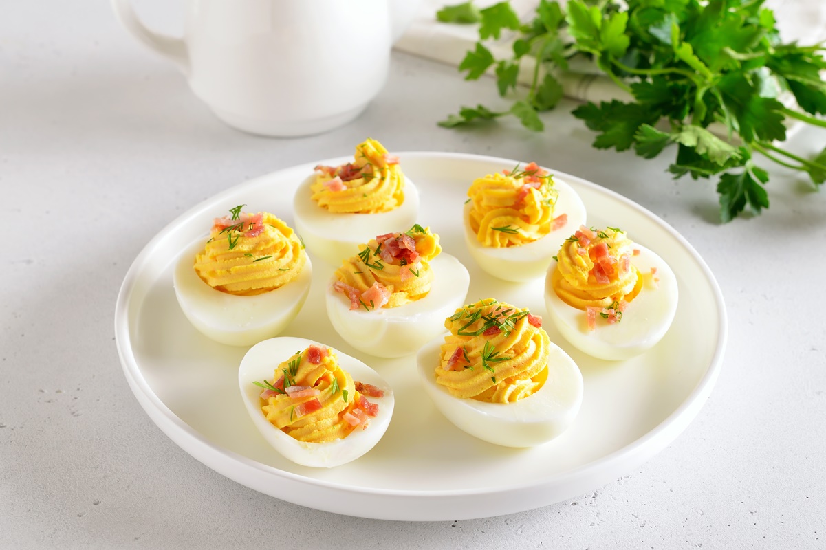 Platou cu ouă umplute cu maioneză și decorate cu șuncă și mărar