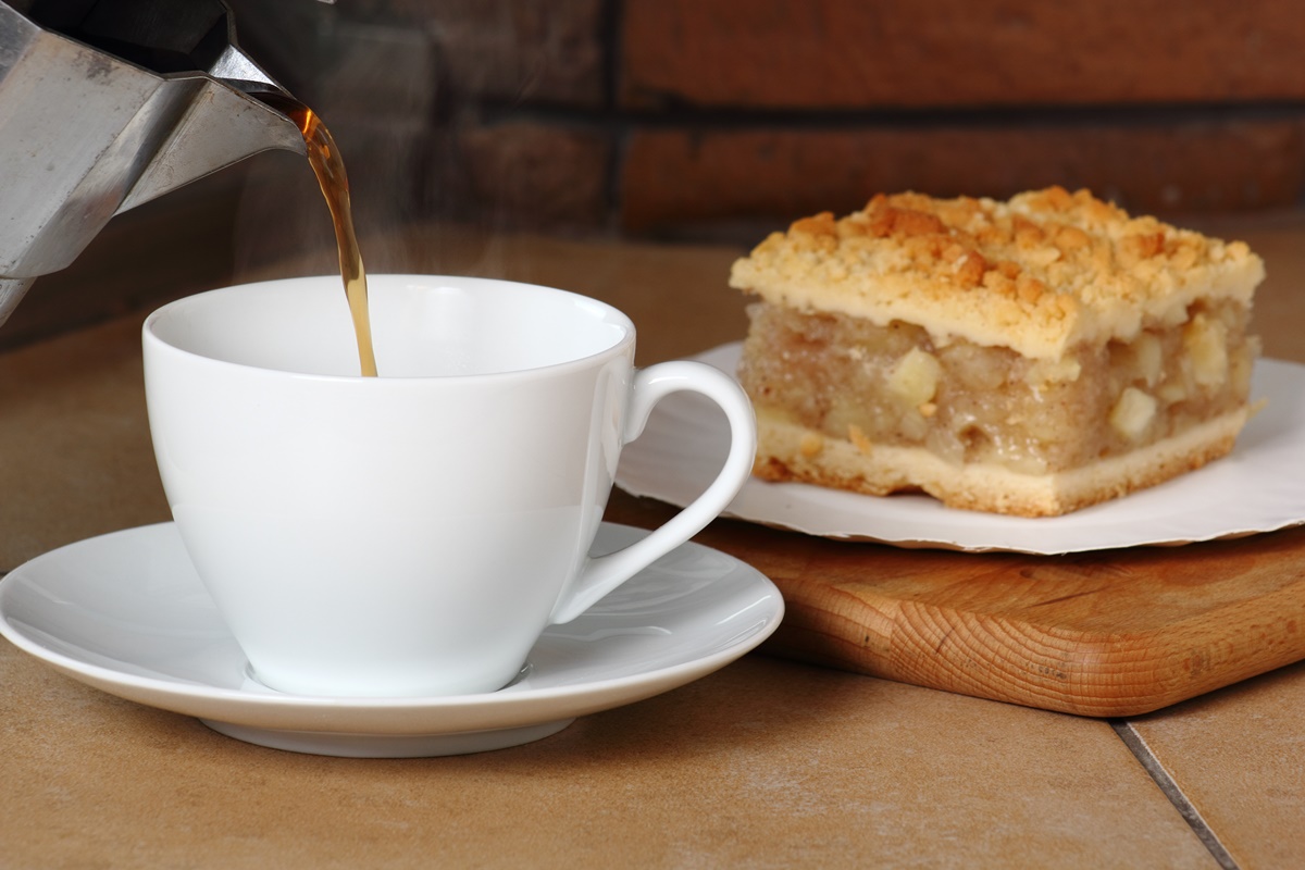 Porție de prăjitură de post cu mere, alături de o ceașcă cu cafea