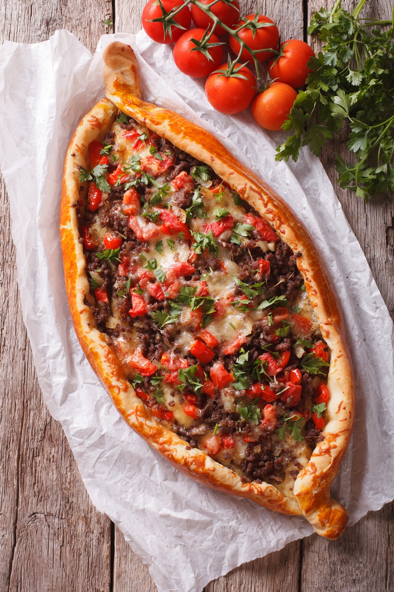Pizza turcească pe hârtie de copt, alături de roșii