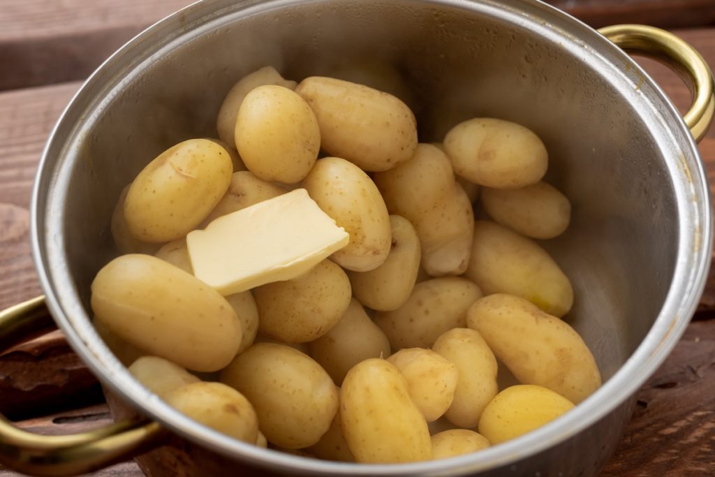 Cartofi fierți în oală, cu o bucată de unt