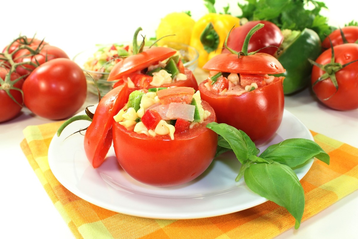 Trei roșii umplute cu salată de paste și legume pe o farfurie albă