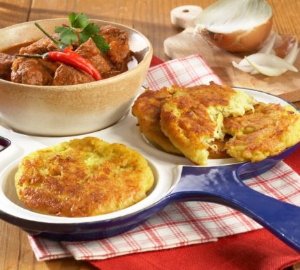 Trei mini omlete cu cartofi rași pe un platou, una secționată, alături de un bol cu carne și o ceapă
