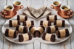 Rulouri de bezea cu ciocolată pe un platou, alături de cești cu cafea - Rețete de prăjituri din albușuri