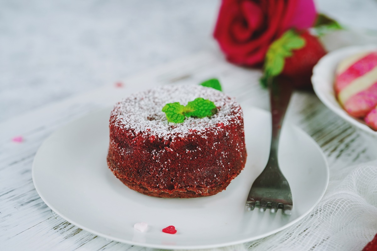 Porție de Red Velvet Lava Cake decorată cu zahăr pudră și frunze de mentă