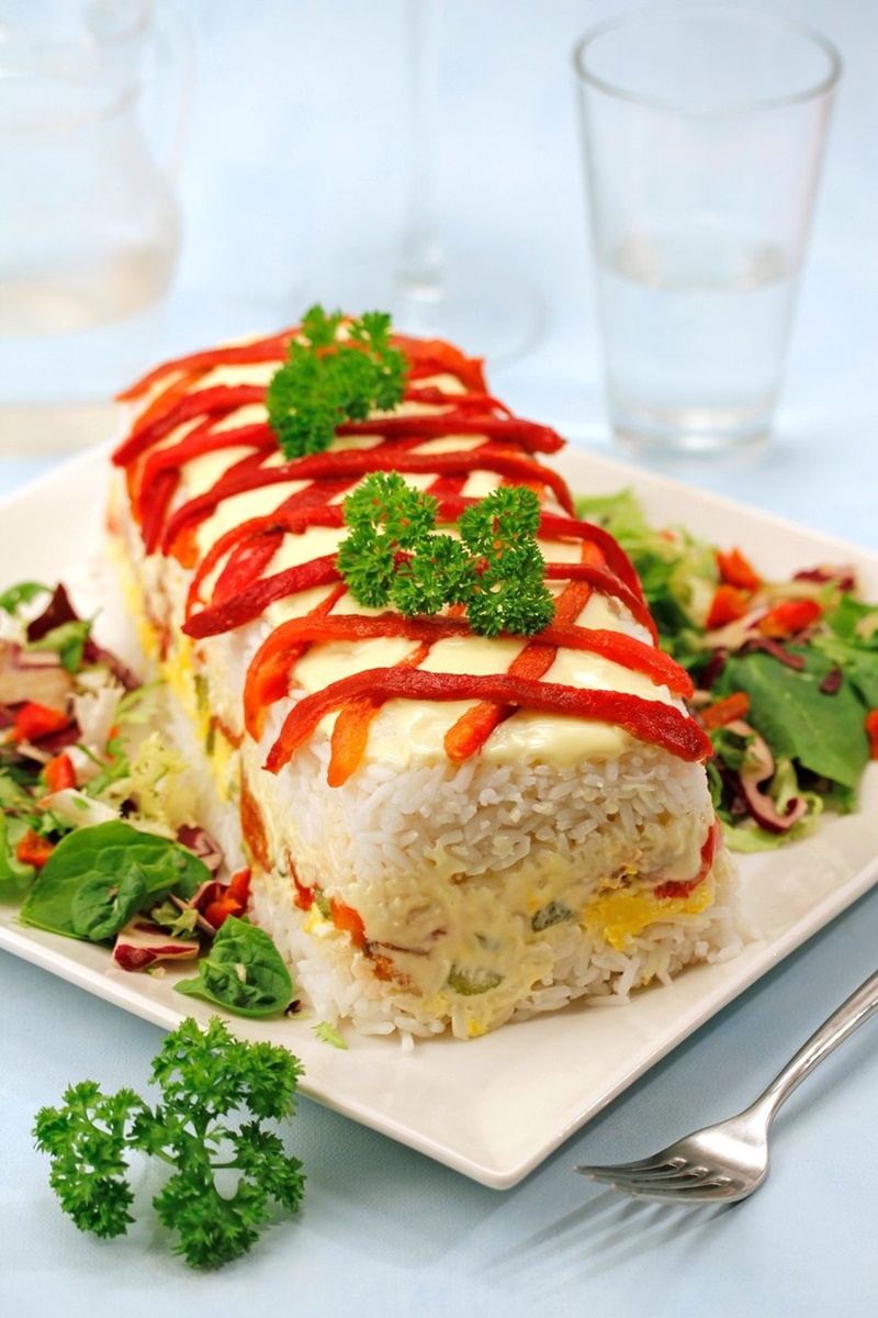 Terină de orez cu ton și ardei copți pe un platou alb cu salată