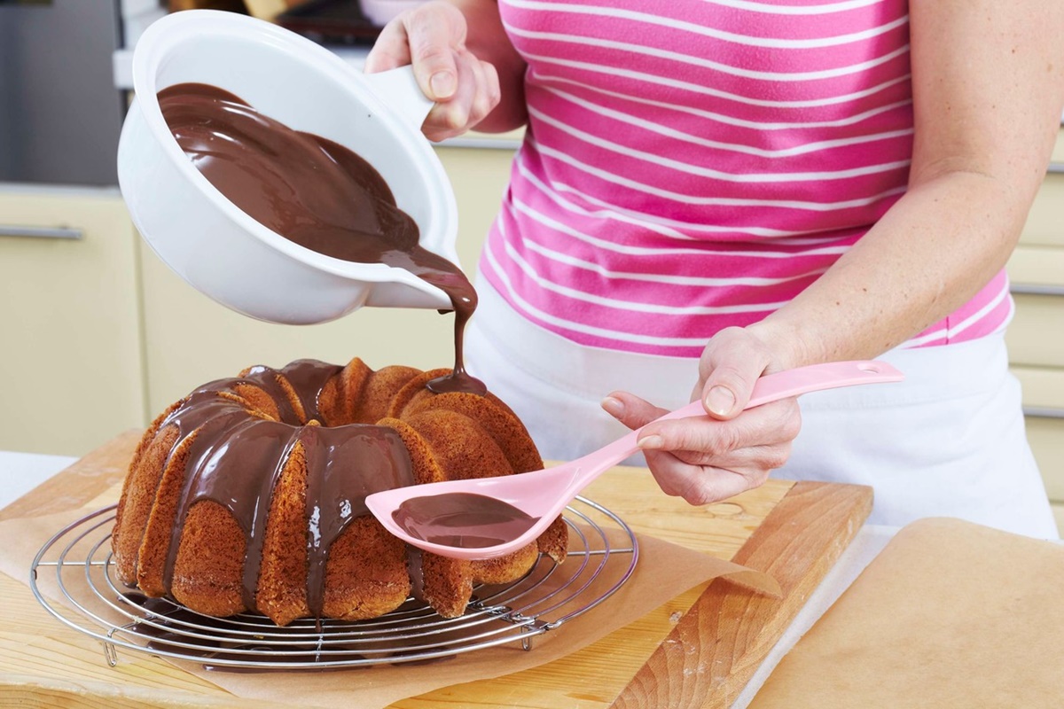 Femeie glazurând cu ciocolată checul cu iaurt și cireșe