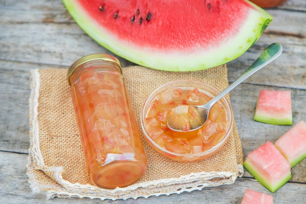 Dulceață din coji de pepene roșu în borcan și în bol cu linguriță alături de o felie de pepene / Shutterstock