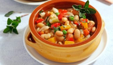 Porție de Mâncare de fasole boabe cu legume caramelizate, în bol maro cu mânere