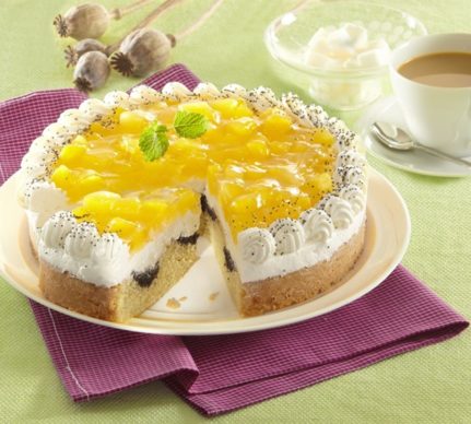 Tort cu compot de dovleac și blat marmorat cu mac porționat pe un platou alb, alături de o ceașcă de cafea, un bol de sticlă și 3 lujere de mac