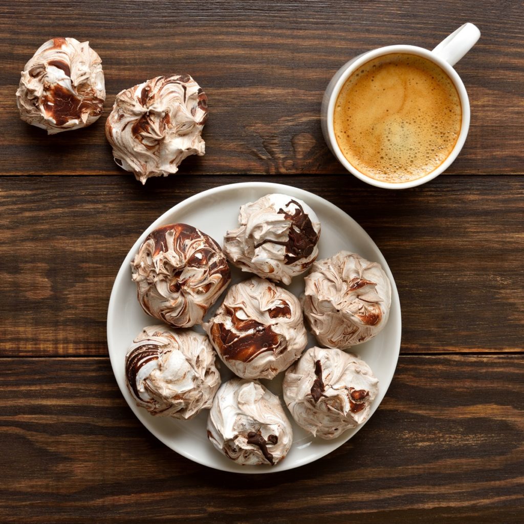 Bezele marmorate cu ciocolată amăruie pe o farfurie și două alături de o ceașcă cu cafea