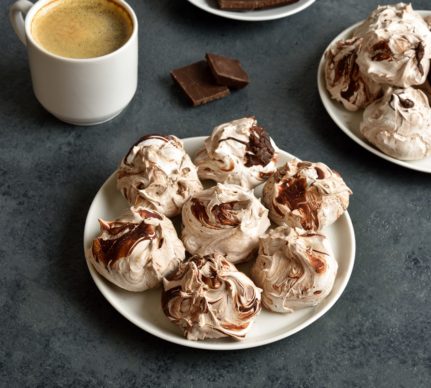 Bezele marmorate cu ciocolată amăruie pe două farfurii alături de o ceașcă de cafea și o farfurie cu ciocolată