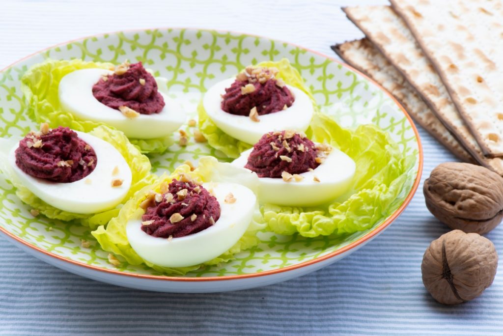 Ouă umplute cu cremă din sfeclă cu hrean și nuci pe frunze de salată verde, așezate pe o farfurie