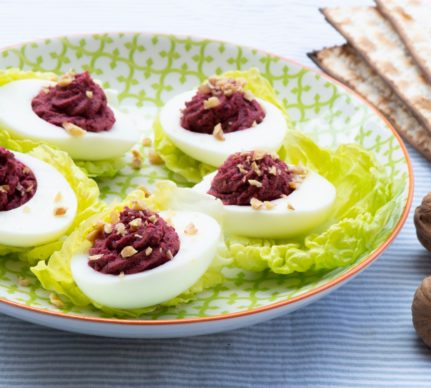 Ouă umplute cu cremă din sfeclă cu hrean și nuci pe frunze de salată verde, așezate pe o farfurie