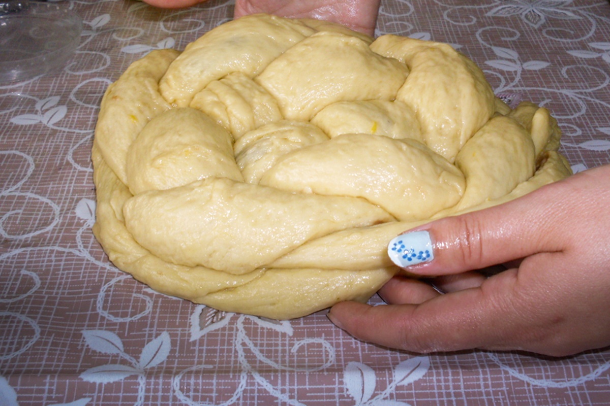 Femeie ținând în mâini aluatul împletit pentru pâine