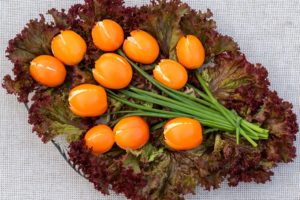 Buchet de lalele din roșii galbene umplute cu brânză și cozi de ceapă verde, pe frunze de salată