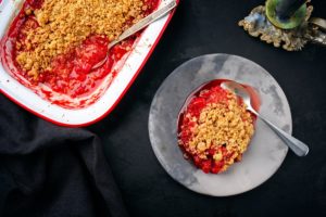 Crumble cu rubarbă și căpșuni în vas și în farfurie cu lingură