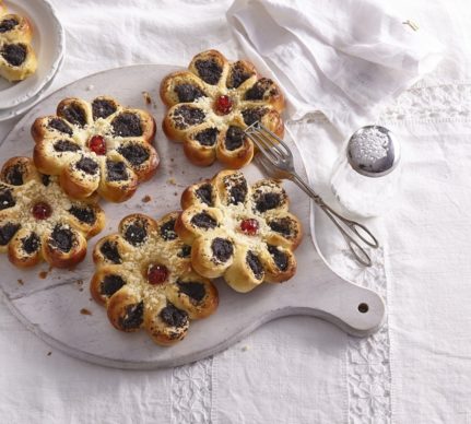 Prăjiturele cu mac în formă de floare pe un platou de lemn șiuna secționată pe o farfurie