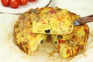 Tortilla de patatas sau omletă spaniolă cu cartofi porționată pe o hârtie de copt