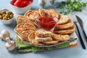 Mini pizza pancakes pe un platou cu un bol de ketchup la mijloc