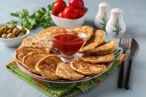 Mini pizza pancakes pe un platou cu un bol de ketchup la mijloc