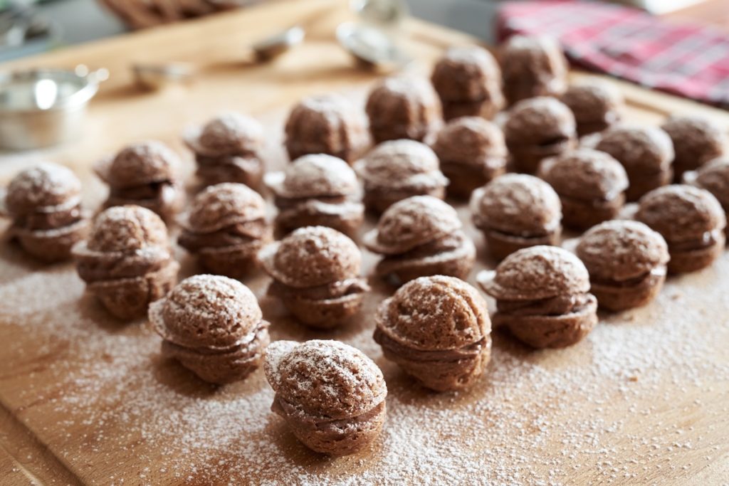 Nuci cu cacao în aluat și cremă de ciocolată și decorate cu zahăr pudră