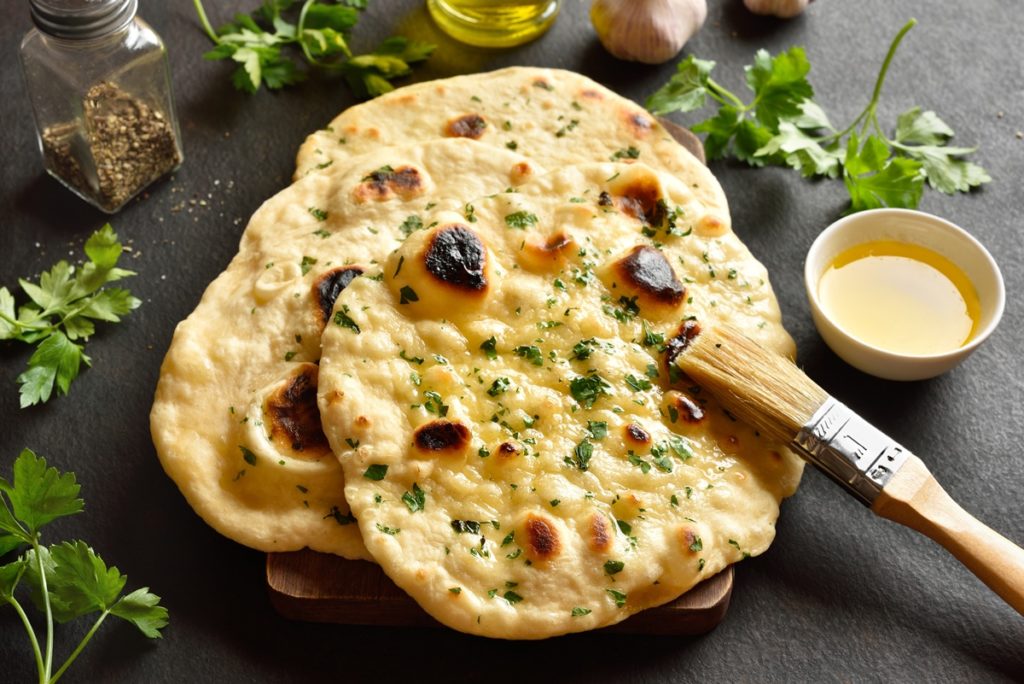 Pasul de ungere pâine indiană naan, cu usturoi și unt, folosind o pensulă