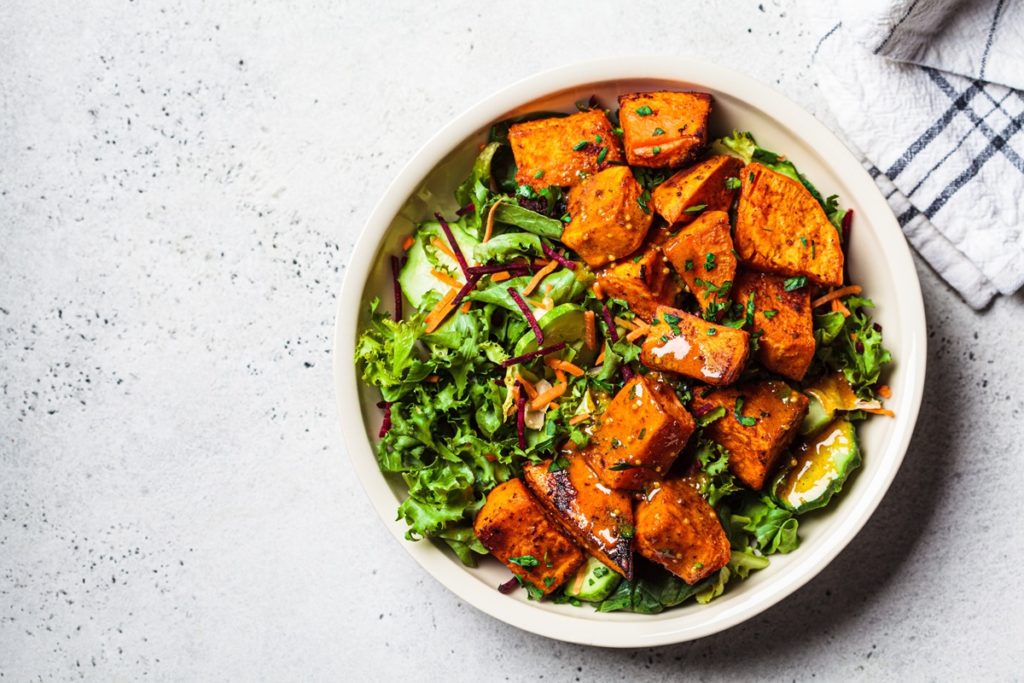 Bol cu salată verde, cartofi dulci, sos de muștar și ceapă roșie