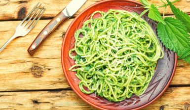 Spaghete cu pesto de urzici în farfurie, furculiță și cuțit