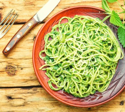 Spaghete cu pesto de urzici în farfurie, furculiță și cuțit