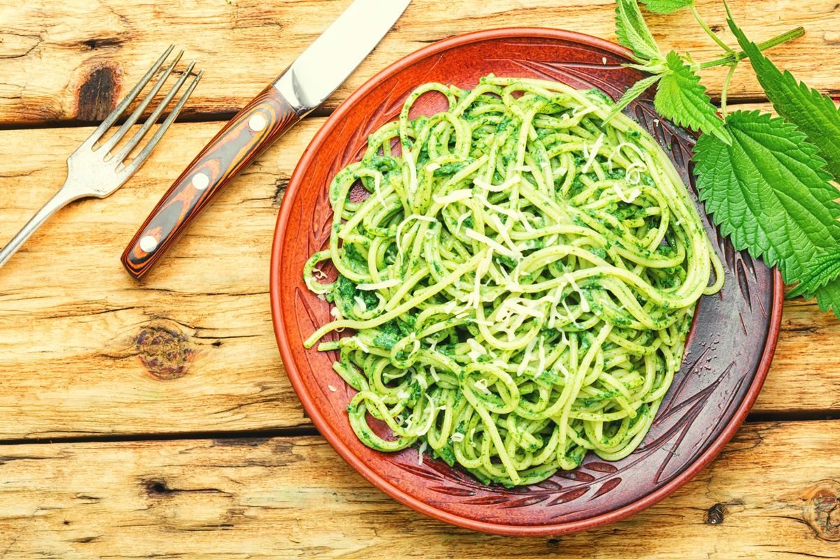 Spaghete cu pesto de urzici în farfurie, furculiță și cuțit