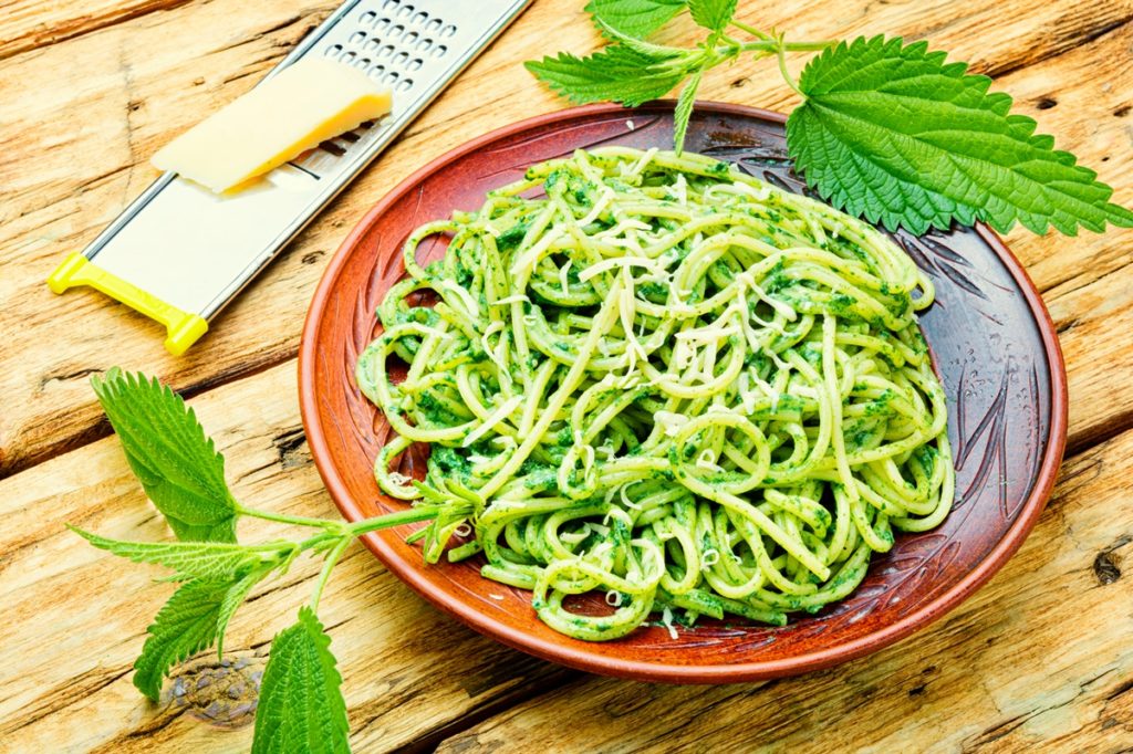 Spaghete cu pesto de urzici alături de o bucată de parmezan și răzătoare
