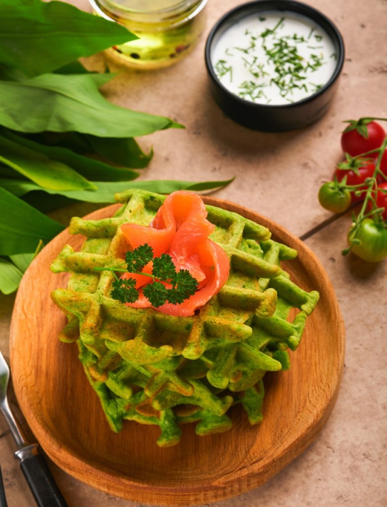 Vafe cu leurdă și spanac decorate cu somon afumat, alături de frunze de leurdă, sos de iaurt și roșii cherry