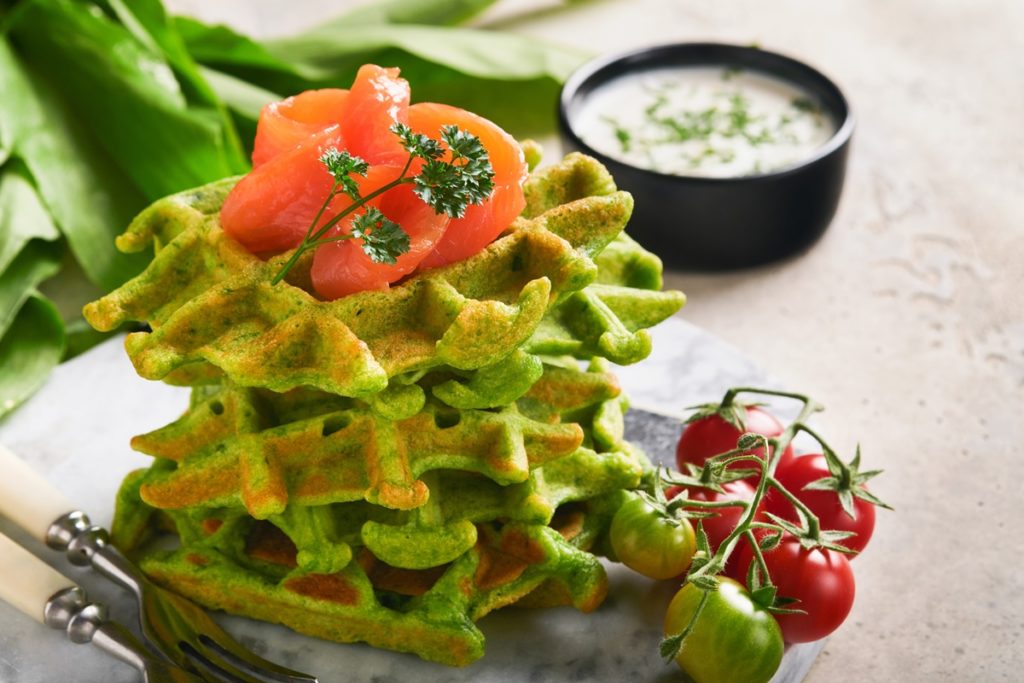 Vafe cu spanac și leurdă, decorate cu somon afumat, alături de frunze de leurdă, sos de iaurt și roșii cherry