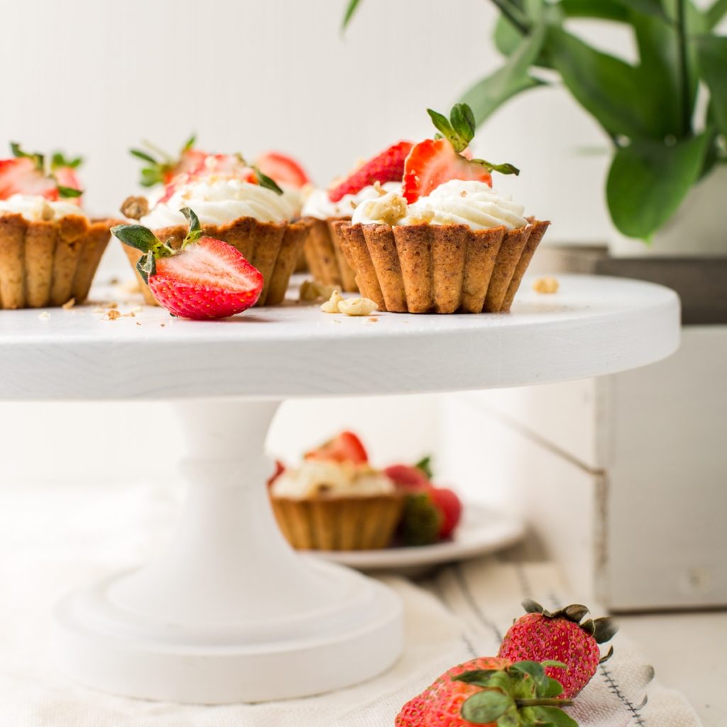 Mini tarte cu căpșuni și cremă de lapte condensat pe un platou cu picior