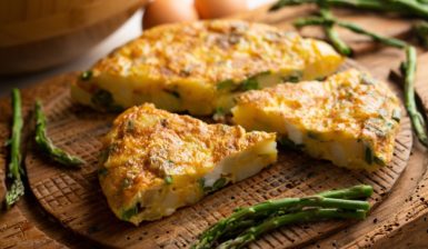 Omletă cu sparanghel și cartofi porționată pe un tocător