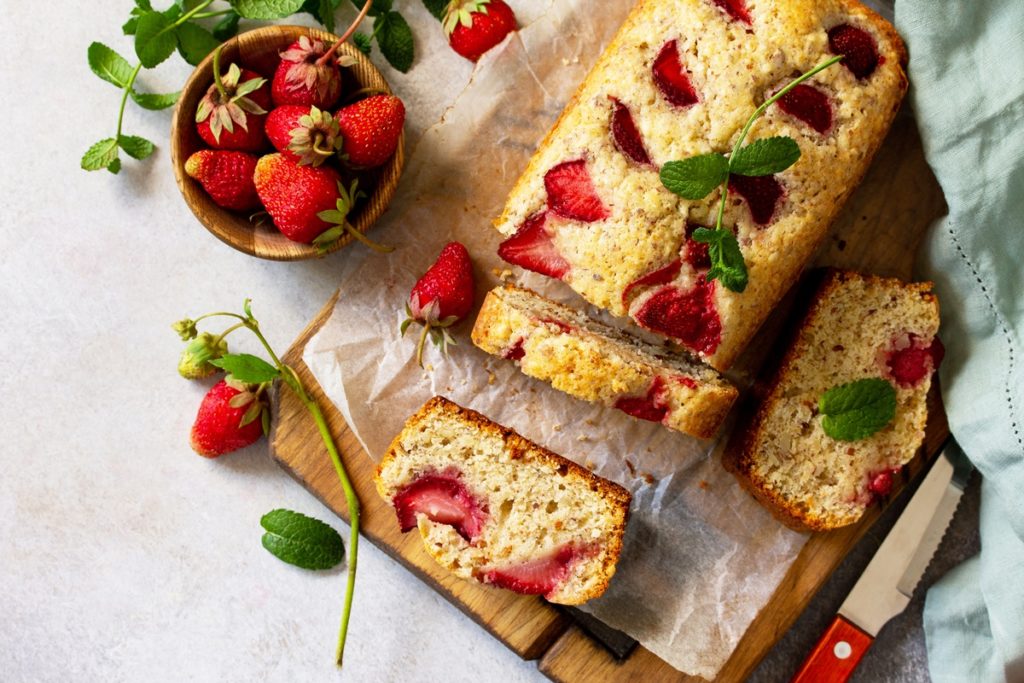 Chec cu cocos și căpșuni feliat și un bol cu căpșuni