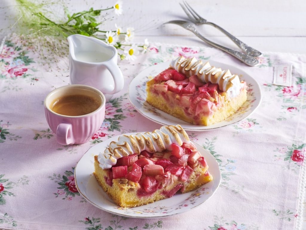 Două porții de pandișpan cu rubarbă și bezea, alături de o ceașcă cu cafea și o latieră