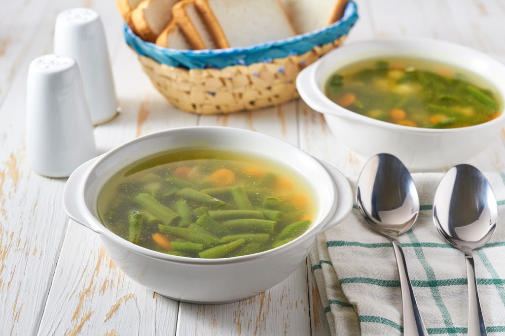 Două boluri cu supă din păstăi de fasole și un coș cu pâine