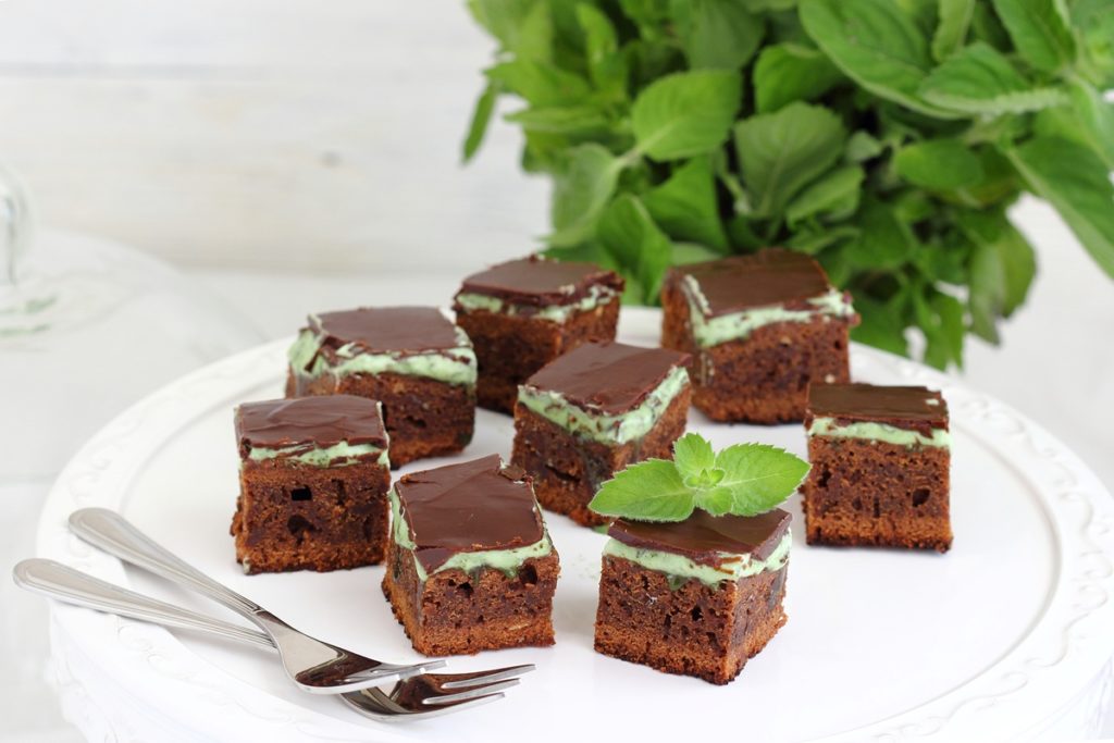 Negresă cu cremă de mentă și ciocolată porționată, alături de furculițe și frunze de mentă