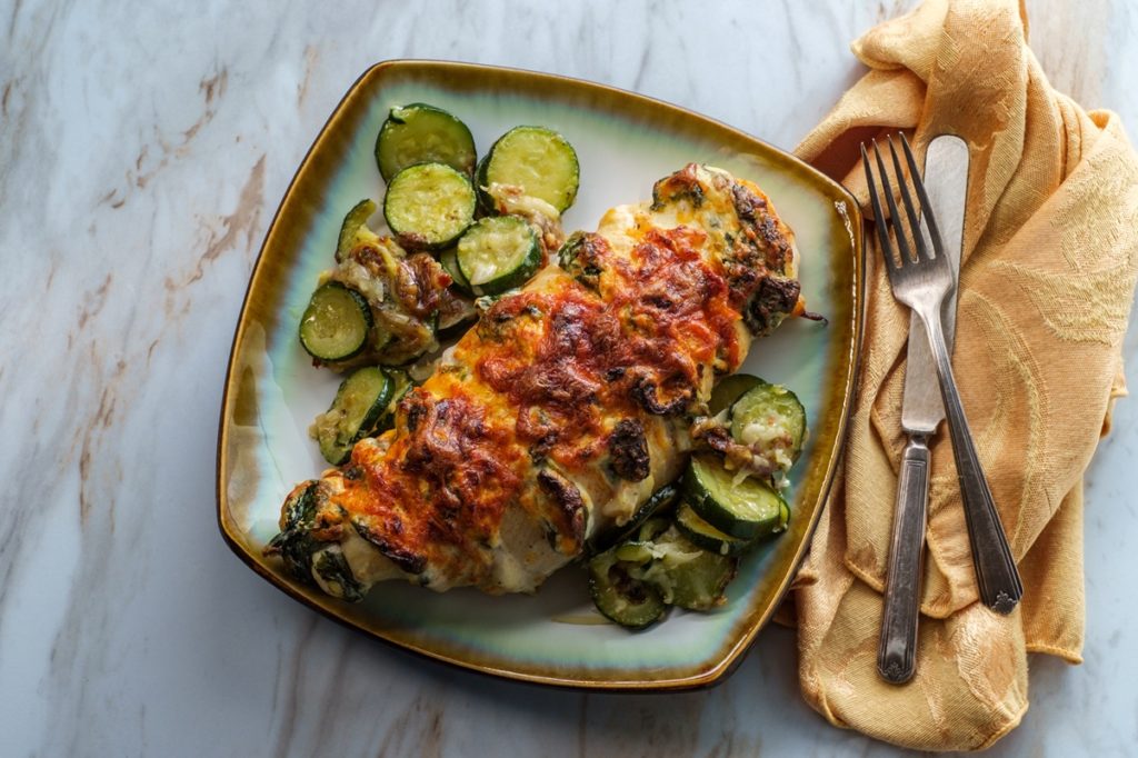 Porție de pui Hasselback pe un platou cu salată de castraveți