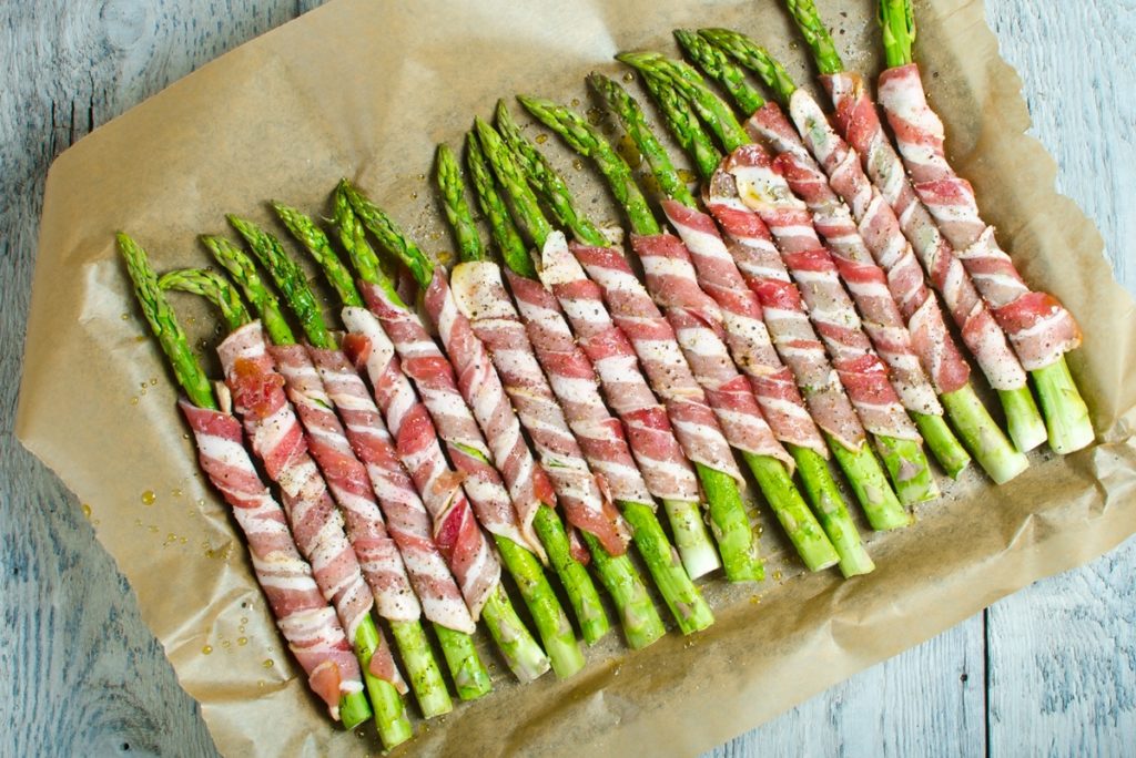 Sparanghel în felii de bacon într-o tavă, pe hârtie de copt