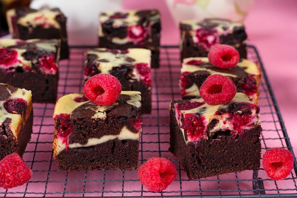 Porții de Cheesecake Brownie cu zmeură pe un grătar, decorate cu zmeură